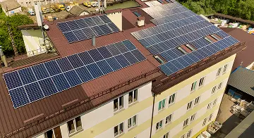 Fotovoltaické panely na střeše bytového domu.