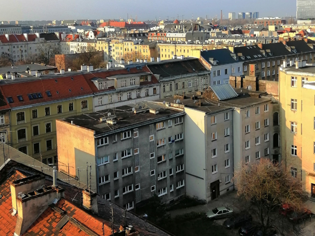 Panorama města s bytovými domy v odpoledním slunci, pohled z vnitrobloku.